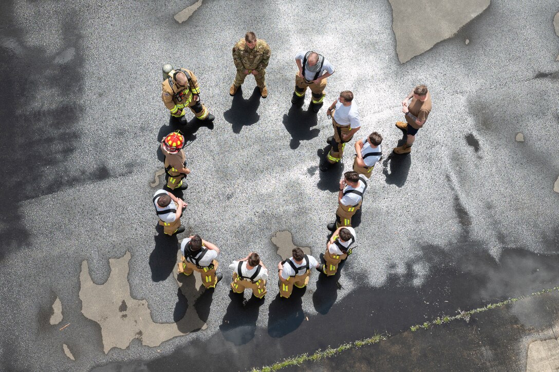 Airmen stand in a circle to receive instruction.