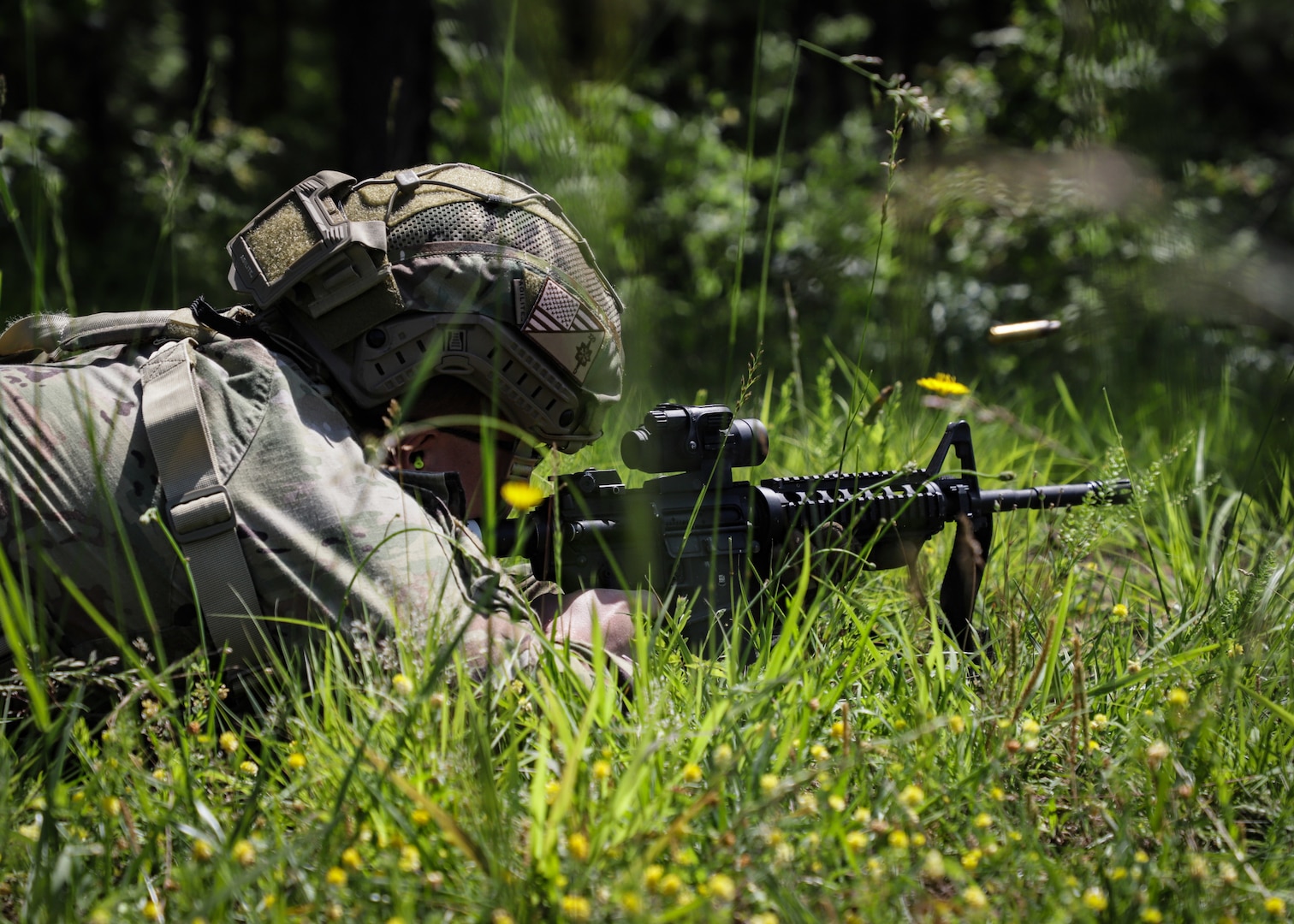 A Soldier shoots a rifle in the prone position in a field.