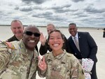 Soldiers and leaders pose together on a runway.
