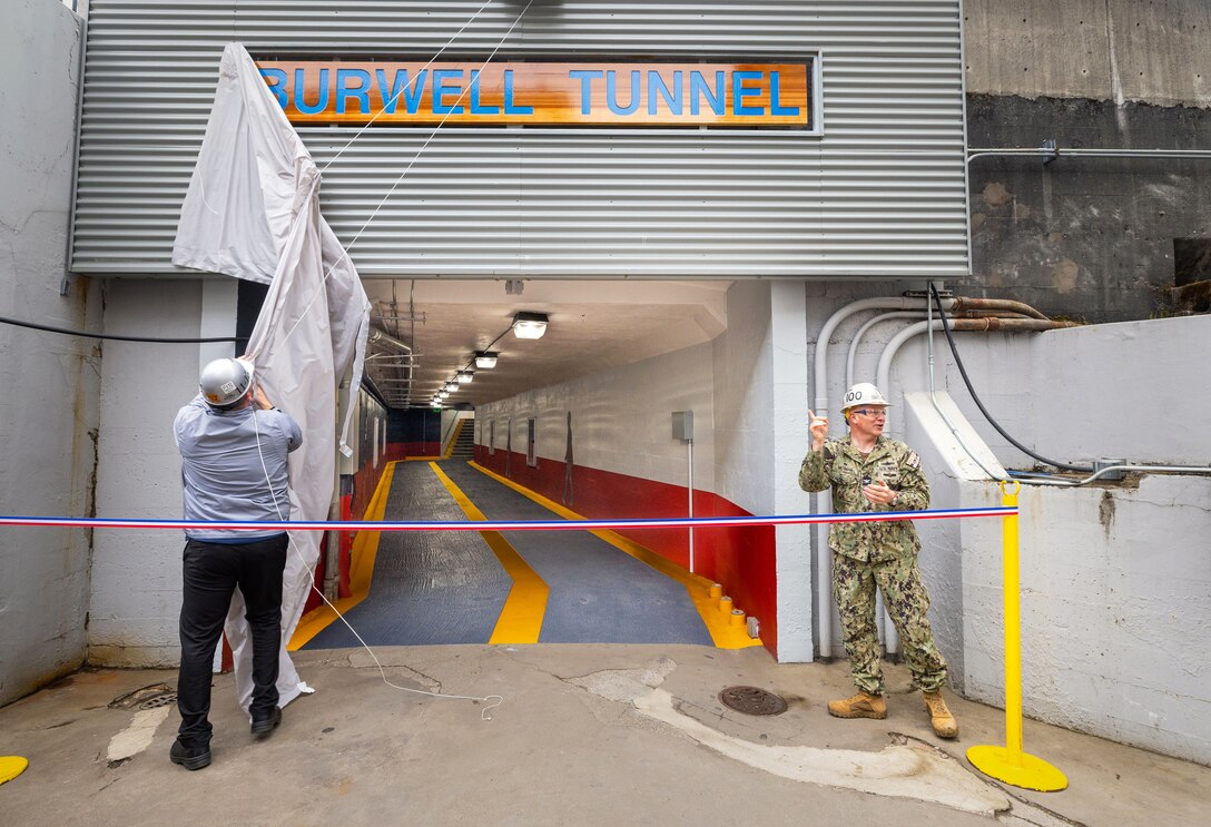 Capt. Jip Mosman, commander, Puget Sound Naval Shipyard & Intermediate Maintenance Facility, in Bremerton, Washington, and Jeremy Stephens, Superintendent, Shop 11/17, Shipfitters & Sheetmetal, unveil a new Burwell Tunnel entrance sign, May 9, 2023, in Bremerton, Washington. (U.S Navy photo by Wendy Hallmark)