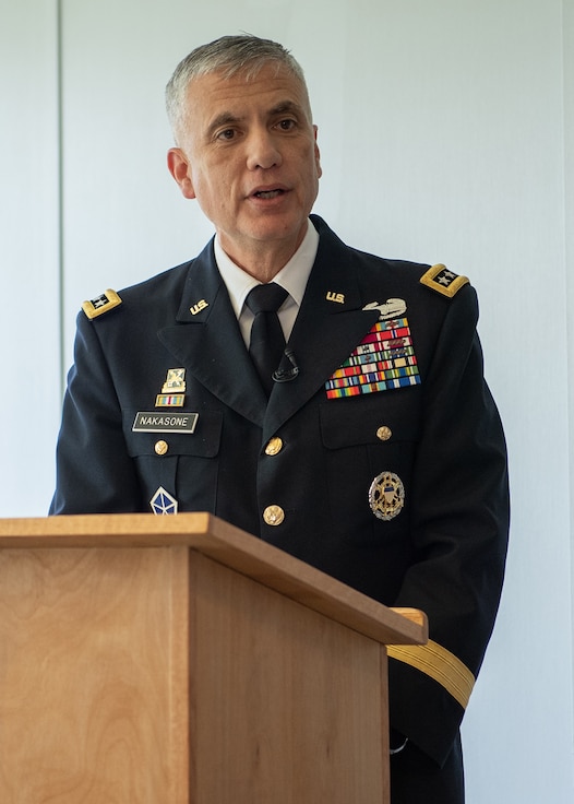 A man in a military uniform speaks from behind a podium