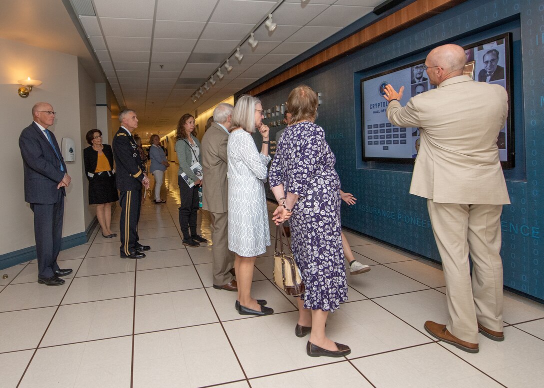 A crowd of people observe an interactive display on a wall.