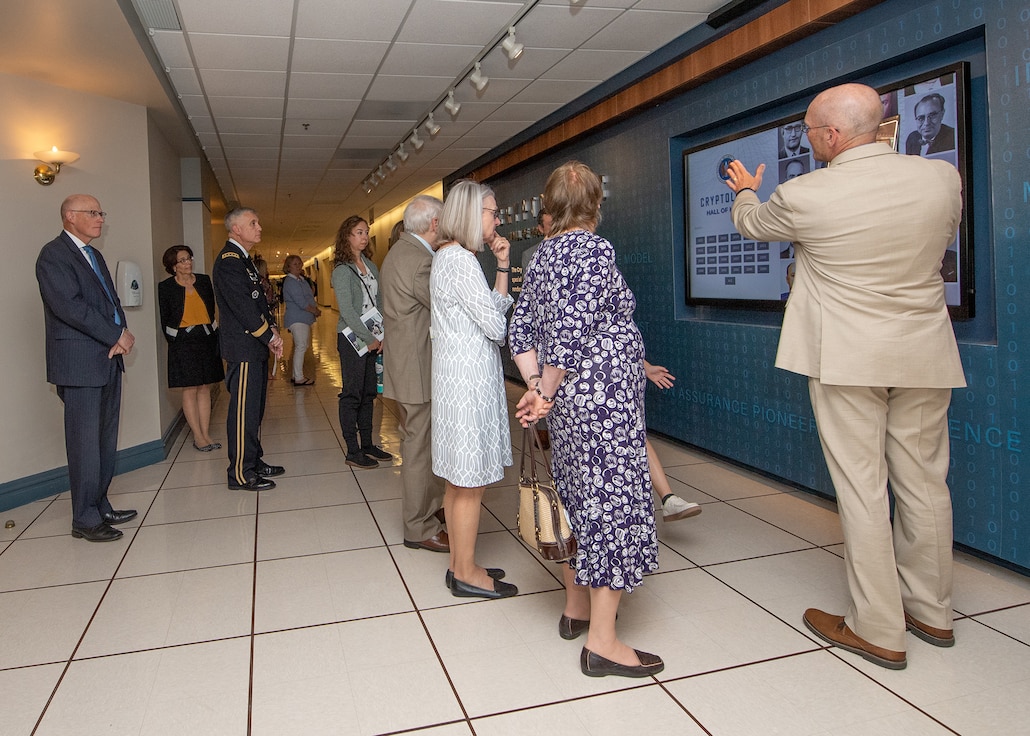 A crowd of people observe an interactive display on a wall.