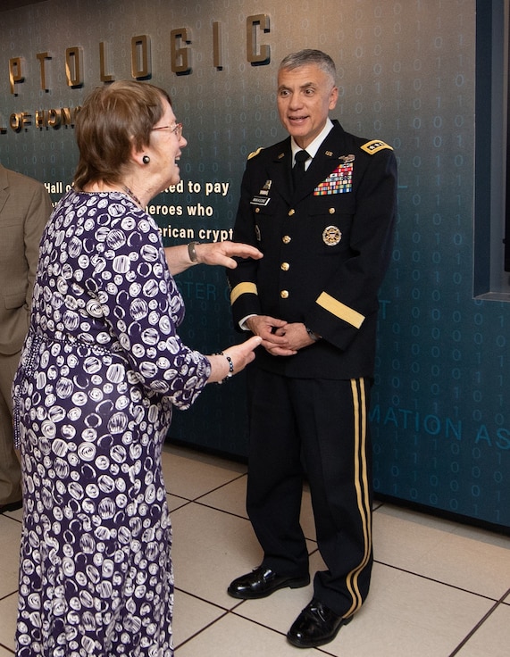 A woman in a purple floral dress tells a story to a man in a military uniform.