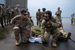 Senior Airman Chandler Davis, a 934th Civil Engineering Squadron emergency management specialist, left, and  Air Force Master Sgt. Brian Tremain, a 934th Aeromedical Evacuation Squadron medical technician, prepare to lift and carry a simulated injured Airman aboard a UH-60 Blackhawk helicopter during a training exercise at the Minneapolis-St. Paul Air Reserve Station, May 5, 2023. All Airmen assisting with patient transfer had to rely on nonverbal communication due to the loud volume of the helicopter rotors. (U.S. Air Force photo by Senior Airman Victoriya Tarakanova)