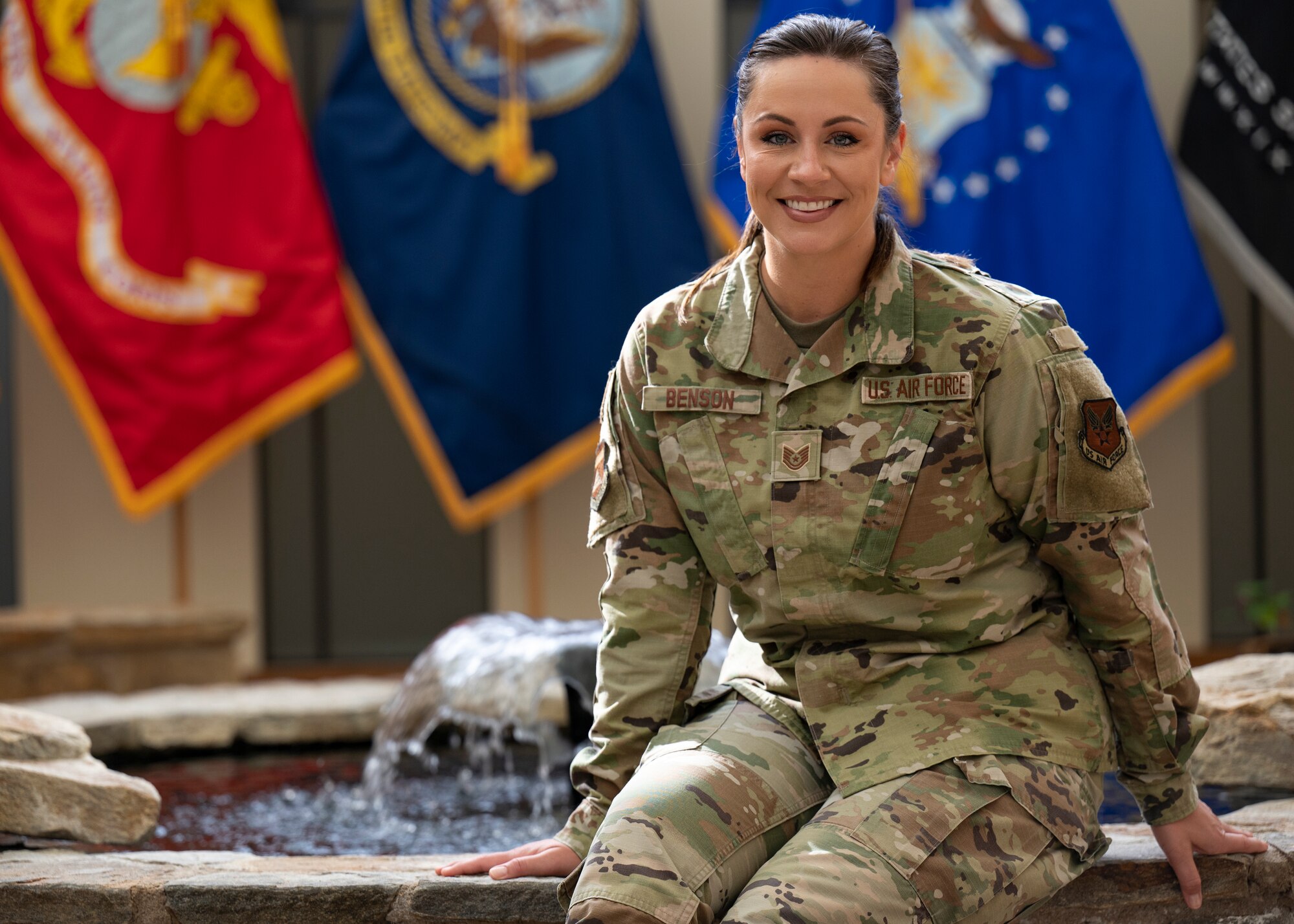 An Airman sits next to a fountain.