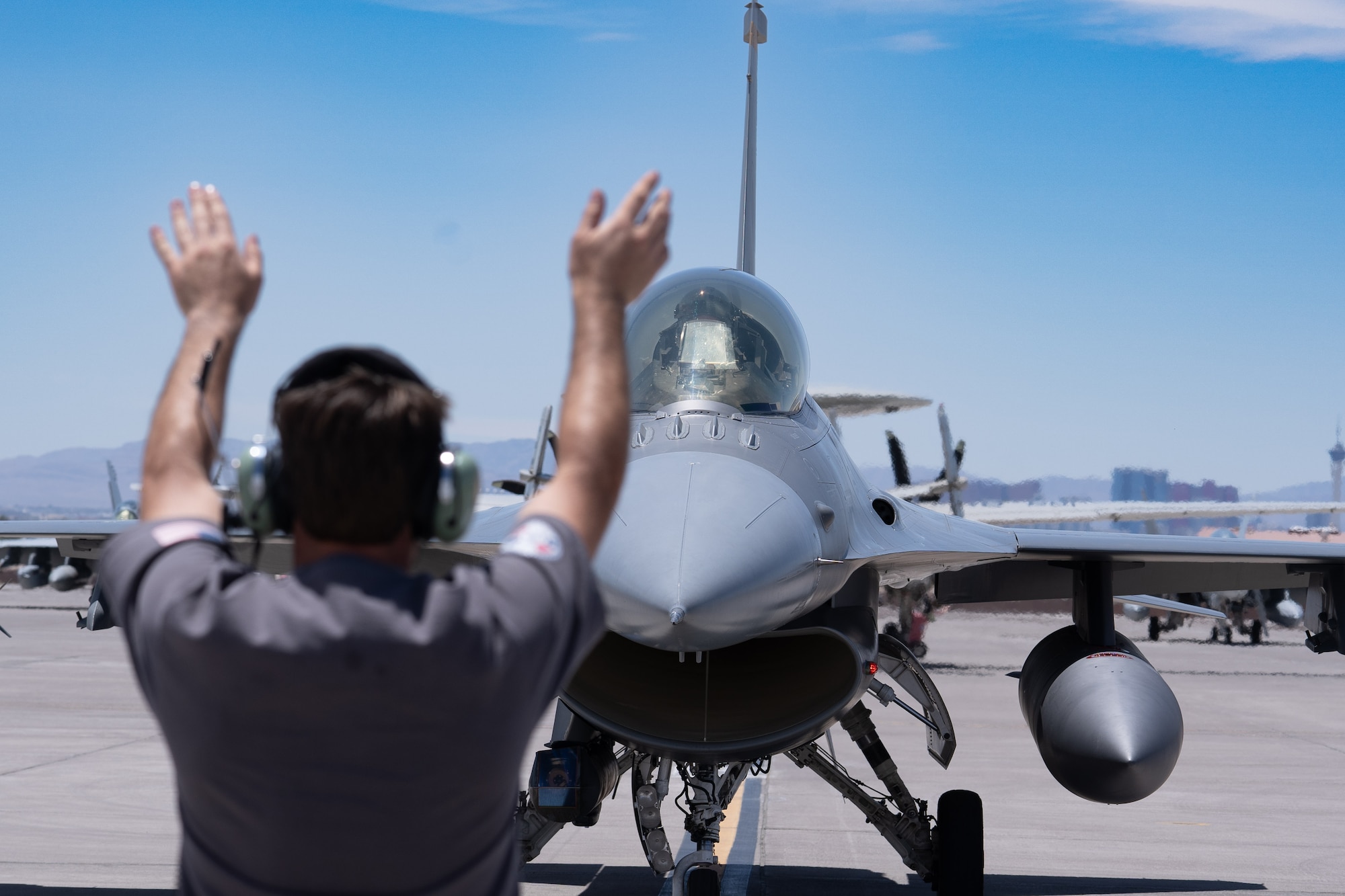 Matthew Leclair, a crew chief contractor for the 839th Aircraft Maintenance Unit, marshals in an F-16D Fighting Falcon at Nellis Air Force Base, Nevada, May 24, 2023.