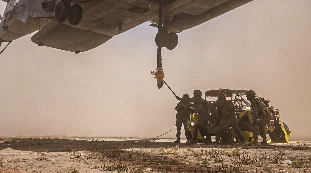 U.S. Marines assigned to Combat Logistics Battalion 15, Combat Logistics Regiment 17, 1st Marine Logistics Group, hook a Polaris MRZR, an ultra-light turbo diesel combat vehicle, beneath a CH-53E Super Stallion attached to Marine Heavy Helicopter Squadron (HMH) 361, Marine Aircraft Group 16, 3rd Marine Aircraft Wing, during external lift operations with a helicopter support team at Marine Corps Base Camp Pendleton, California, May 9, 2023. CLB-15 and HMH-361 worked together to test an innovative lift method utilizing wheel nets to inform publication and standard operating procedure development for the Marine Corps. (U.S. Marine Corps photo by Cpl. Aidan Hekker)