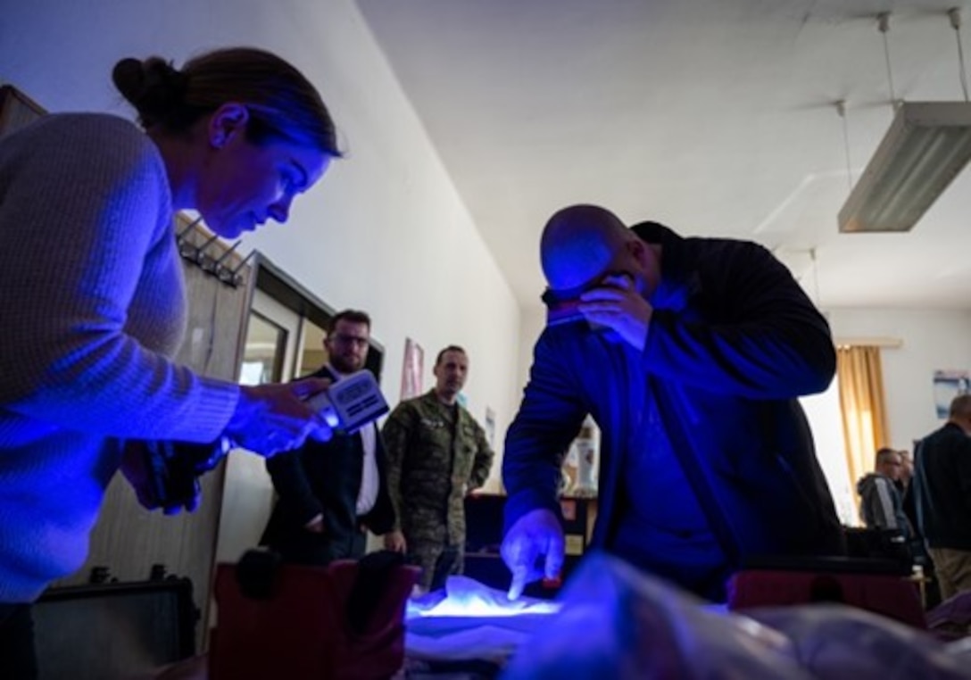 Special Agent Cristin O'Malley, OSI Det. 515 senior enlisted leader, demonstrates the use of lights to detect fragments of materials for a Czech military police member on the second day of a multi-day information exchange in Hronsek, Slovakia, April 25, 2023. The information exchange involved OSI and military police from Eastern European nations, such as Slovakia and the Czech Republic. (U.S. Air Force photo by Thomas Brading, OSI Public Affairs)