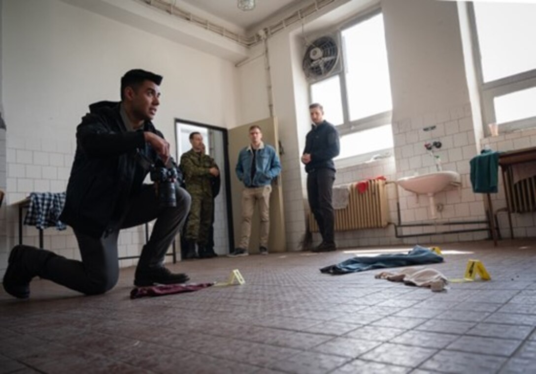 Special Agent Juan Contreras, Office of Special Investigations Det. 515 investigator, explains OSI's approach to crime scene photography during initial investigations, using a simulated sexual assault scenario. Throughout the two-day information exchange, OSI Special Agents discussed investigative methods with Eastern European counterparts and fostered collaboration between OSI and military police from Slovakia and the Czech Republic. (U.S. Air Force photo by Thomas Brading, OSI/PA)