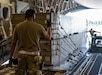 Air Force Staff Sgt. Dave Servida, ramp supervisor for the 436th Aerial Port Squadron, directs weapons cargo bound for Ukraine onto a C-17 Globemaster III during a security assistance mission at Dover Air Force Base, Del., Aug. 19, 2022.