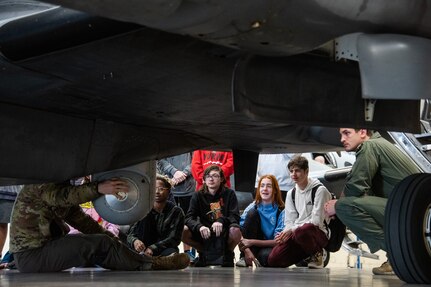 high school students tour the exterior of an MC-12W aircraft