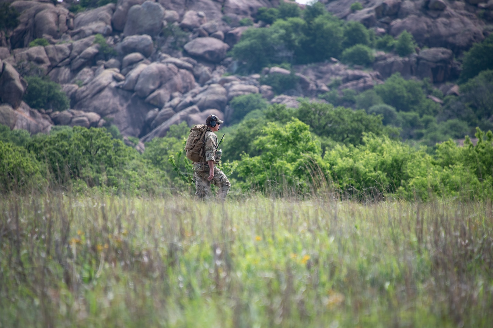 An Airman crosses through a field of grass