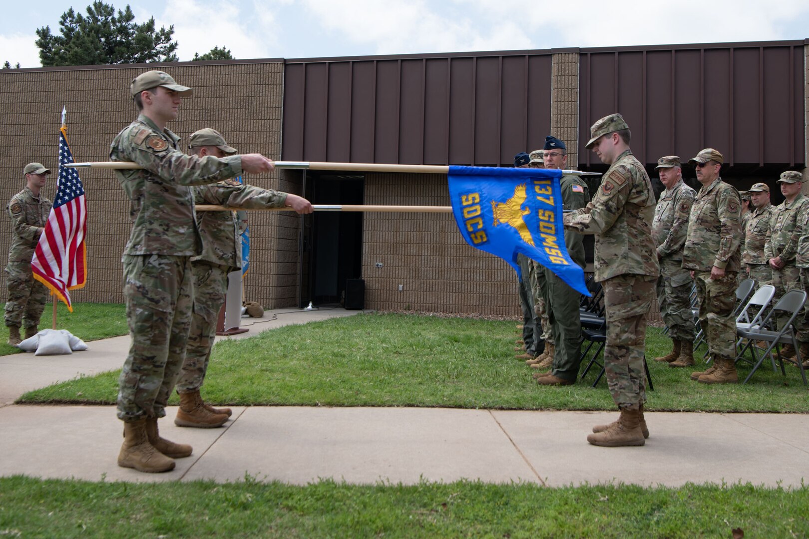 two people hold out guidons during a ceremony with onlookers