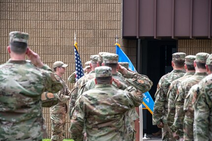 Airmen salute the American flag during an outdoor ceremony