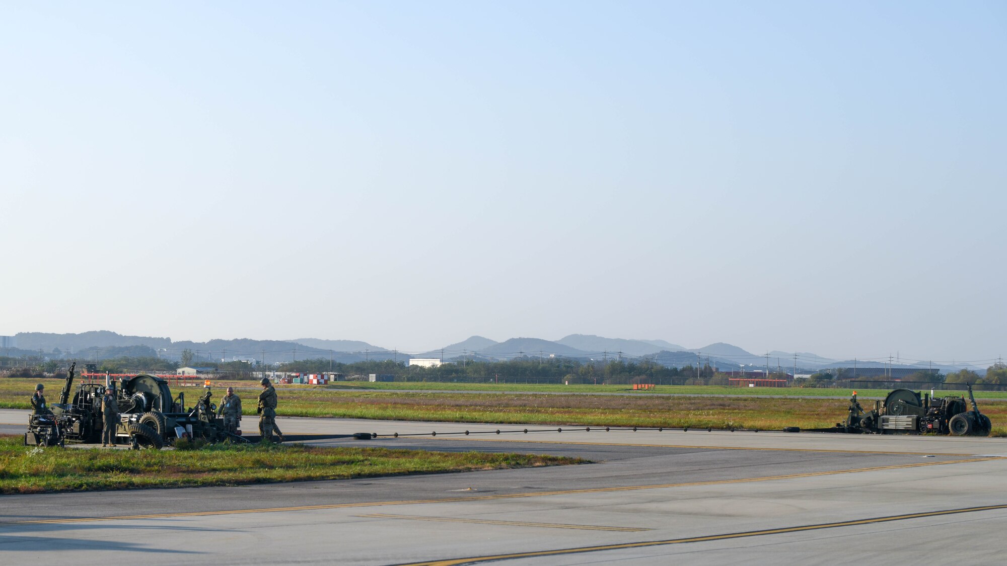 Airmen from the 51st Civil Engineer Squadron view an activated alternate landing strip during Vigilant Defense 24 at Osan Air Base, Republic of Korea, Oct. 29, 2023. The ALS converts a taxiway into a runway, allowing pilots to operate despite damaged runways. This enables pilots to execute the Fight Tonight mission during contingencies. VD24 is a routine training event that tests the military capabilities across the peninsula, allowing combined and joint training at both the operational and tactical levels. (U.S. Air Force photo by Airman 1st Class Chase Verzaal)