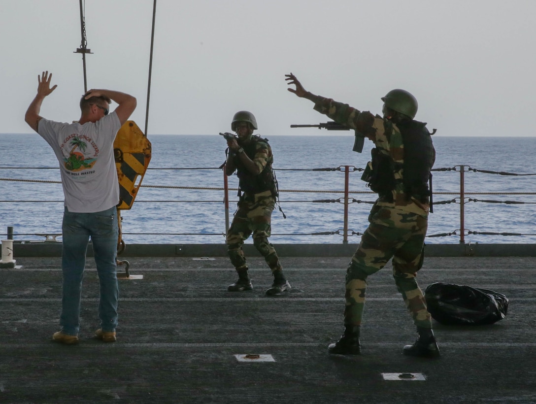 Senegalese Compagnie Fusilier de Marin Commandos (COFUMACO) aboard the USS Hershel “Woody” Williams surround a role player during exercise Grand African Navy Exercises for Maritime Operations (NEMO), Oct. 10, 2023. The USS Hershel "Woody" Williams and embarked Marines from II Marine Expeditionary Force, under the tactical command and control of Task Force 61/2, are on a scheduled deployment in the U.S. Naval Forces Europe and Africa area of operations, employed by U.S. Sixth Fleet to defend U.S., allied and partner interests. (U.S. Marine Corps photo by Lance Cpl. Aydan Millette)