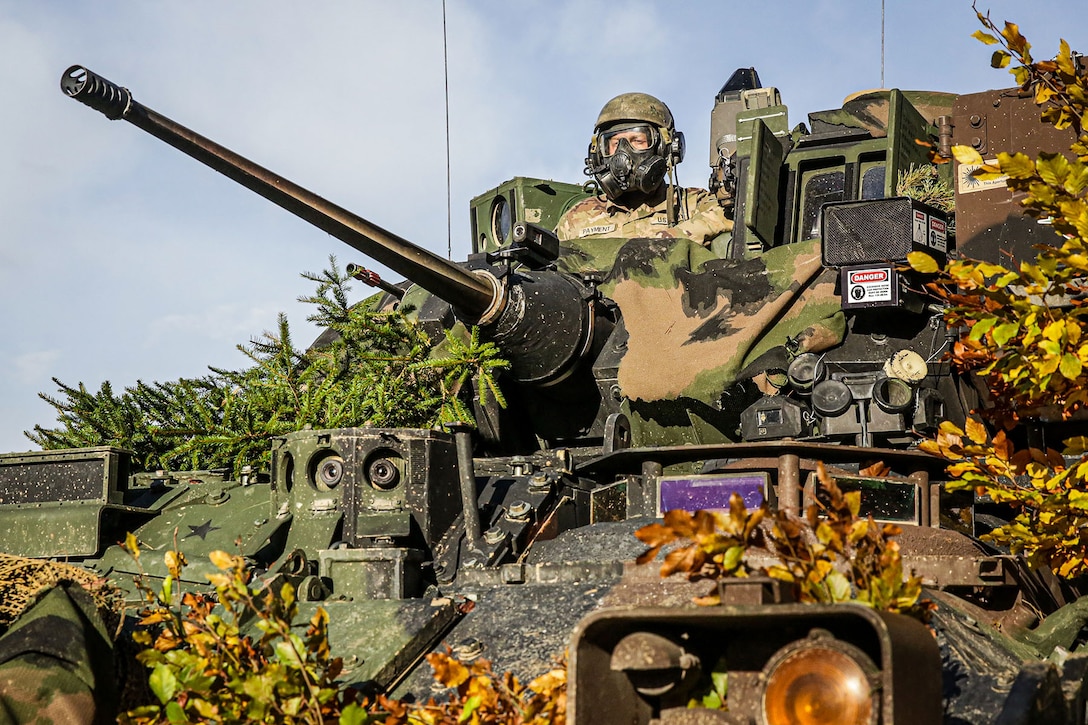 A soldier sitting in a tank scans the area.