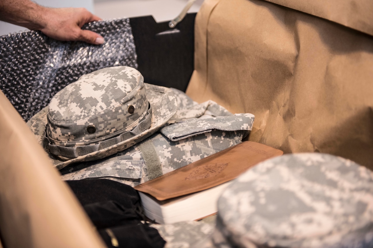 A Boonie hat and book sit on top of a pile of belongings.