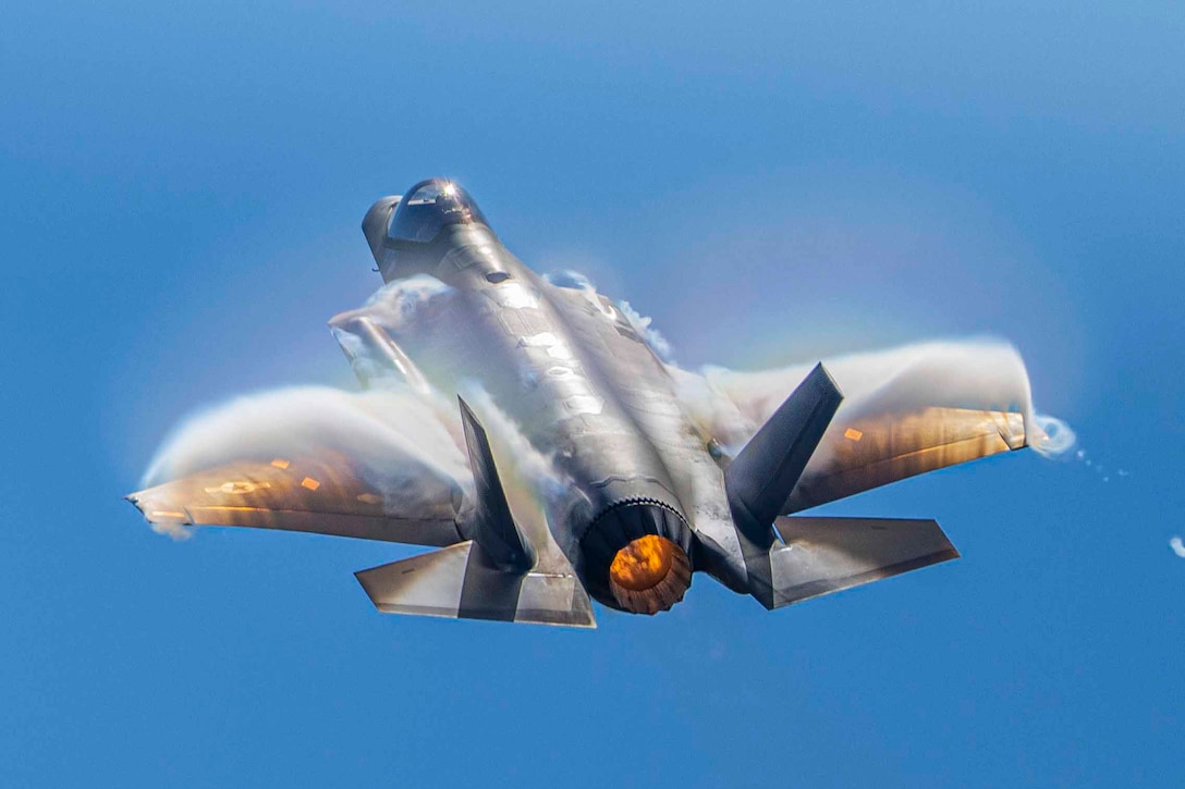 An airborne aircraft creates vapor on its wings.