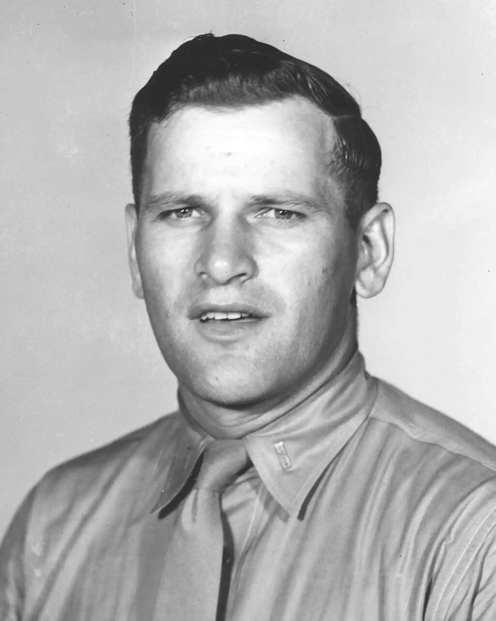 A person in a tie smiles for a black and white photo.