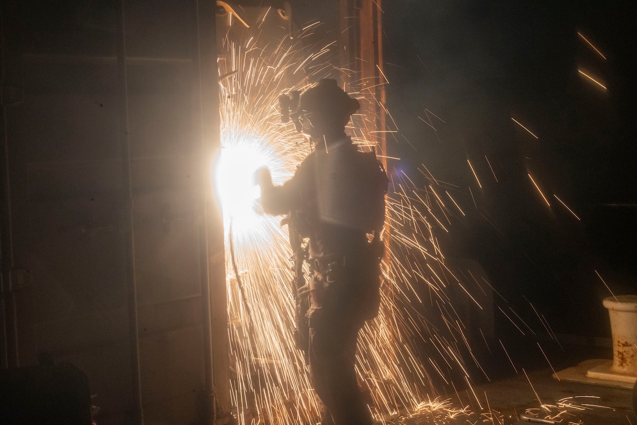 Sparks fly as a Marine breaches a door.