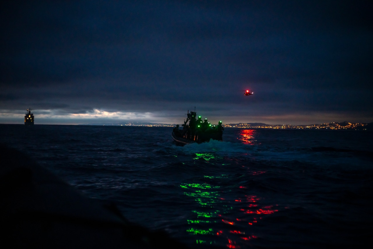 Marines in an inflatable boat close in on a target at night.