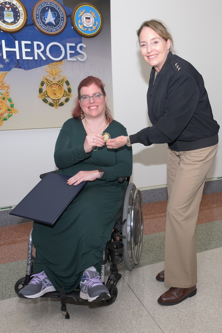 A Navy officer congratulates a civilian for an award win.
