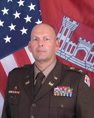 Photo of POD Deputy Commander, COL Christopher W. Crary wearing AGSU uniform in front of the USACE and National colors