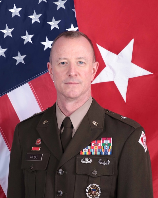 Photo of POD Commanding General, Kirk E. Gibbs wearing AGSU in front of the USACE and National colors