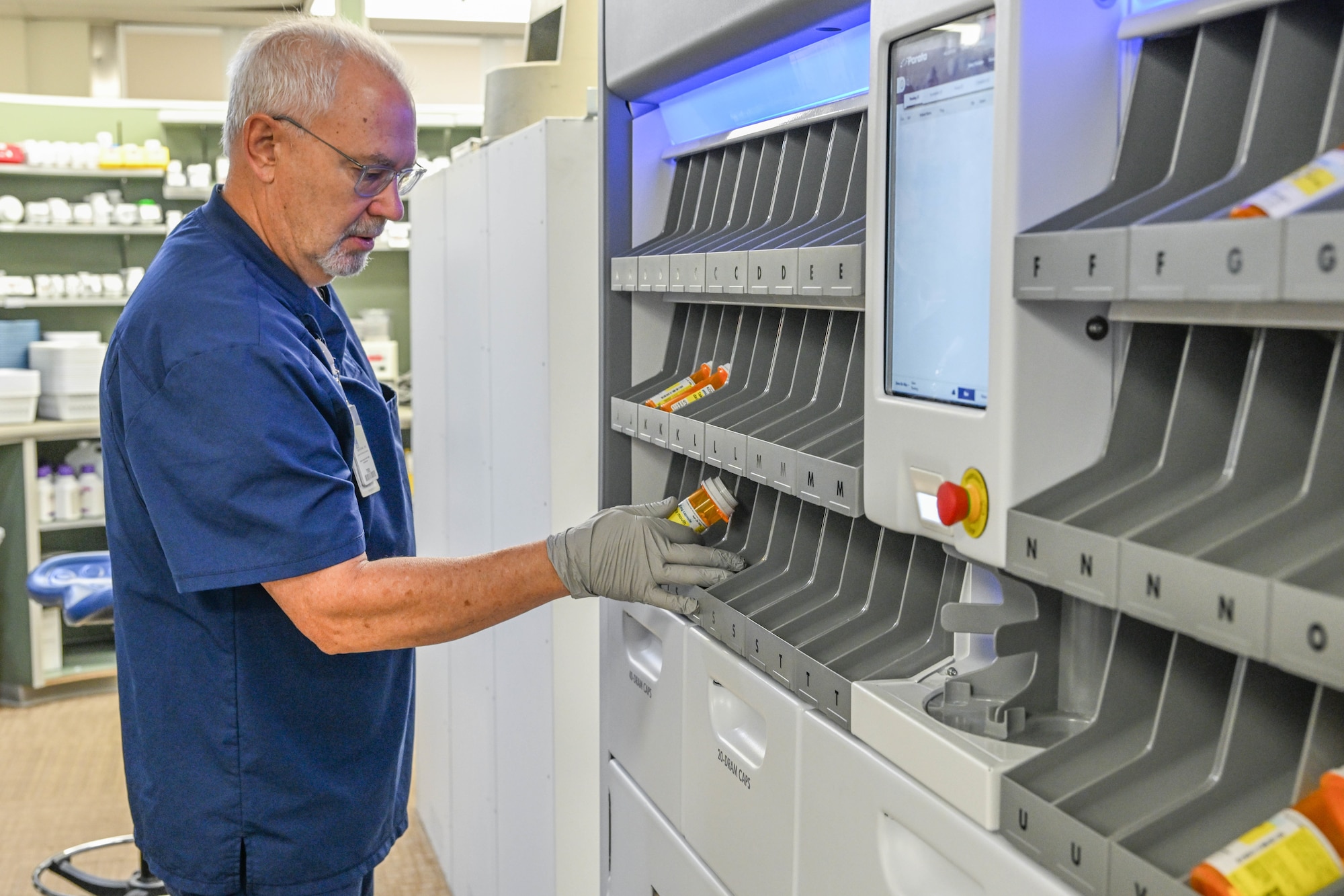 Blake Nelson, 75th Medical Group pharmacist, retrieves a prescription vial from the Parata Max 2 automated medication filling robot Oct. 26, 2023, at Hill Air Force Base