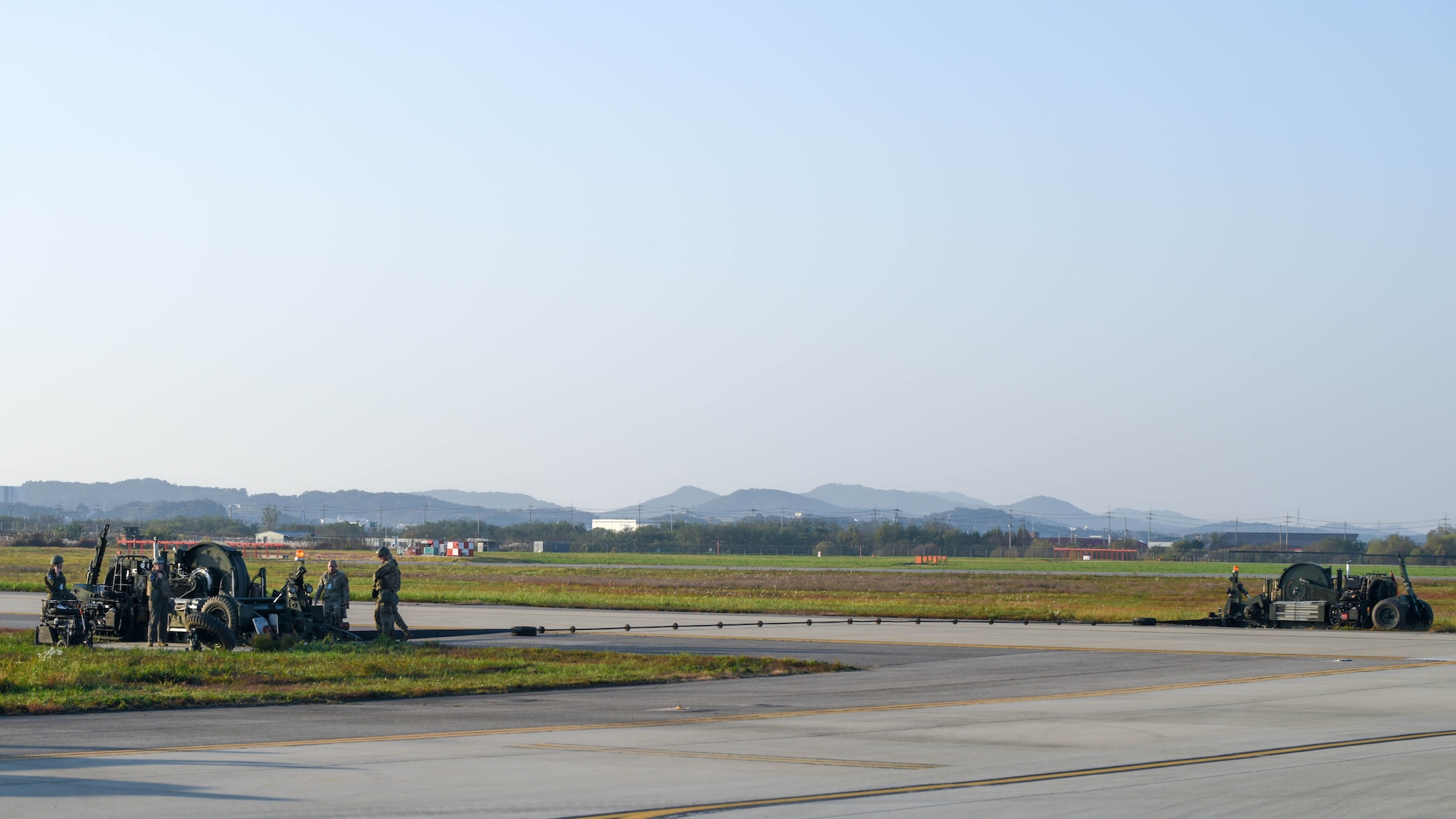 Airmen from the 51st Civil Engineer Squadron view an activated alternate landing strip during Vigilant Defense 24 at Osan Air Base, Republic of Korea, Oct. 29, 2023. The ALS converts a taxiway into a runway, allowing pilots to operate despite damaged runways. This enables pilots to execute the Fight Tonight mission during contingencies. VD24 is a routine training event that tests the military capabilities across the peninsula, allowing combined and joint training at both the operational and tactical levels. (U.S. Air Force photo by Airman 1st Class Chase Verzaal)