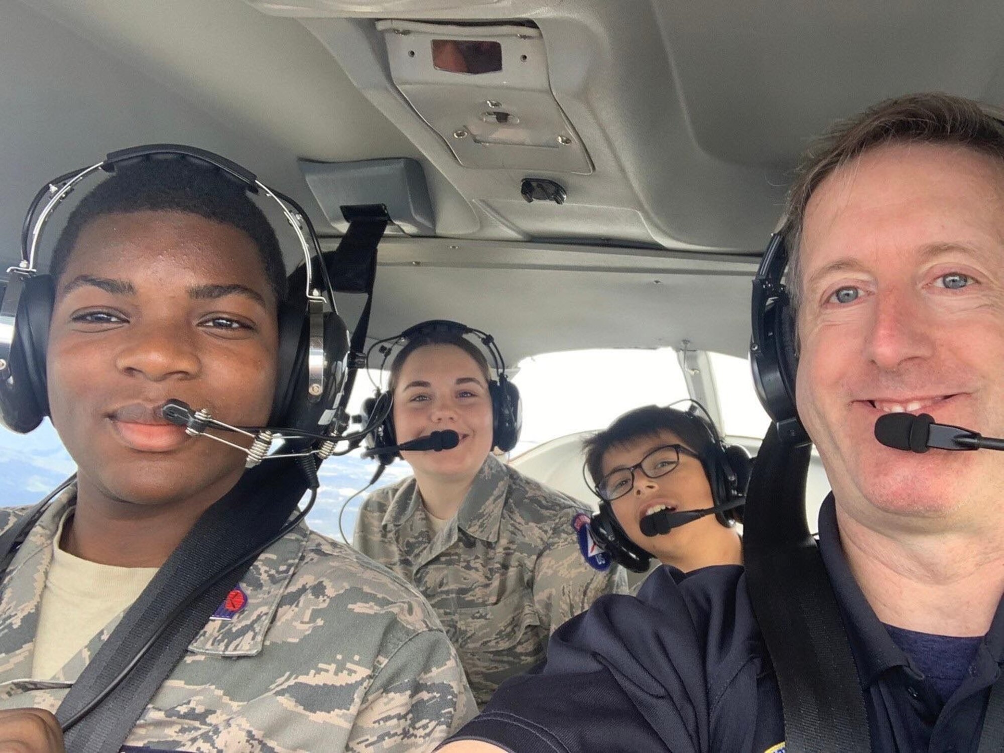 Civil Air Patrol Capt. Jake Kadish, Yokota Flight Training Center chief pilot, takes a photo with Cadet Staff Sgt. Jonathan Burke, Cadet Airman William Qureshi, and Cadet Airman Basic Danni Waldo while 3,ooo feet above Tokyo, Japan, Oct. 20-22, 2023.