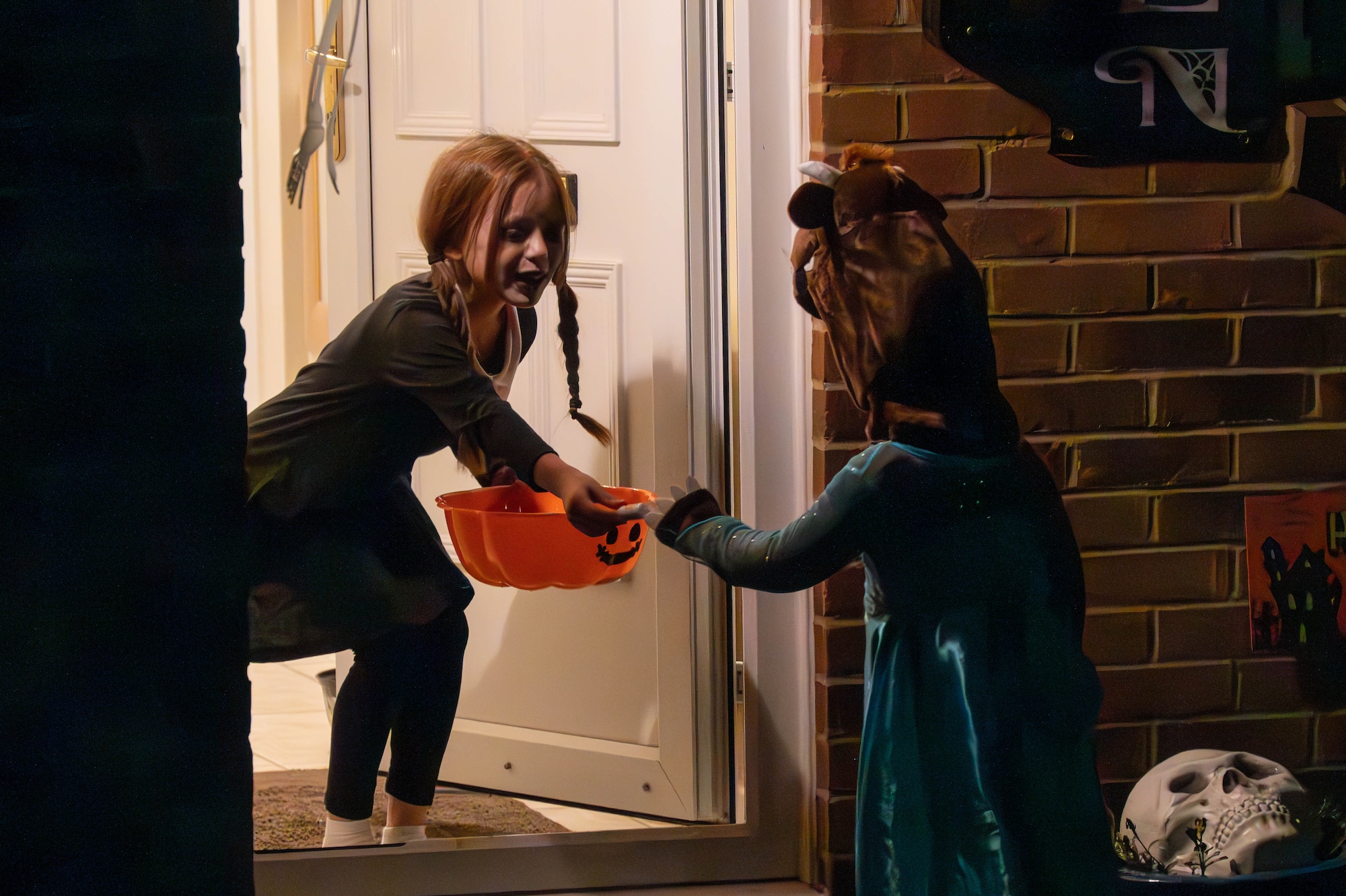 One child hands out candy to another child in a doorway