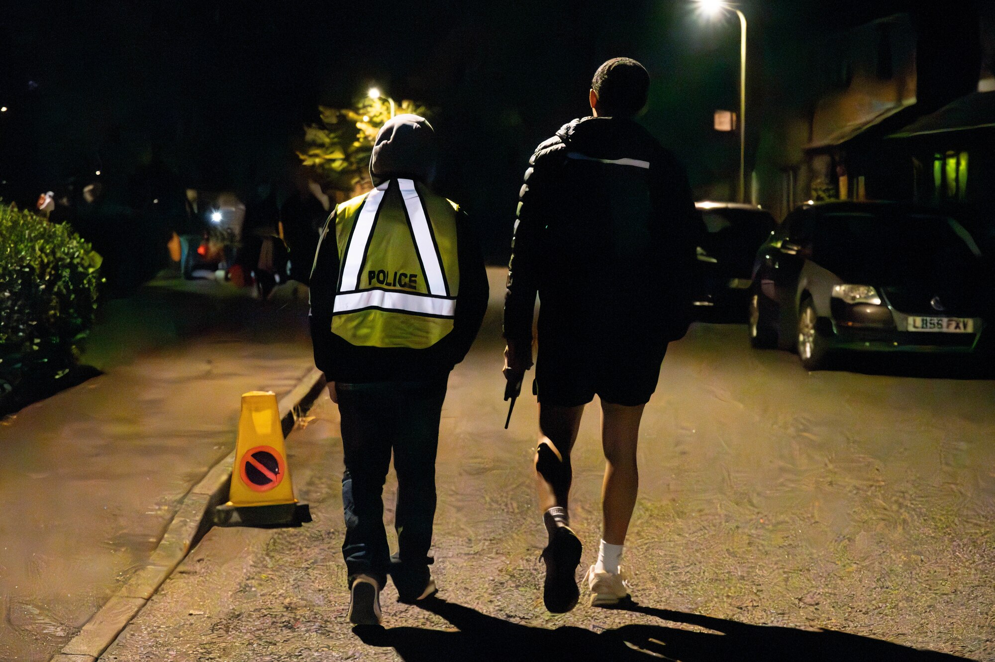 Security volunteers walk down a street at night