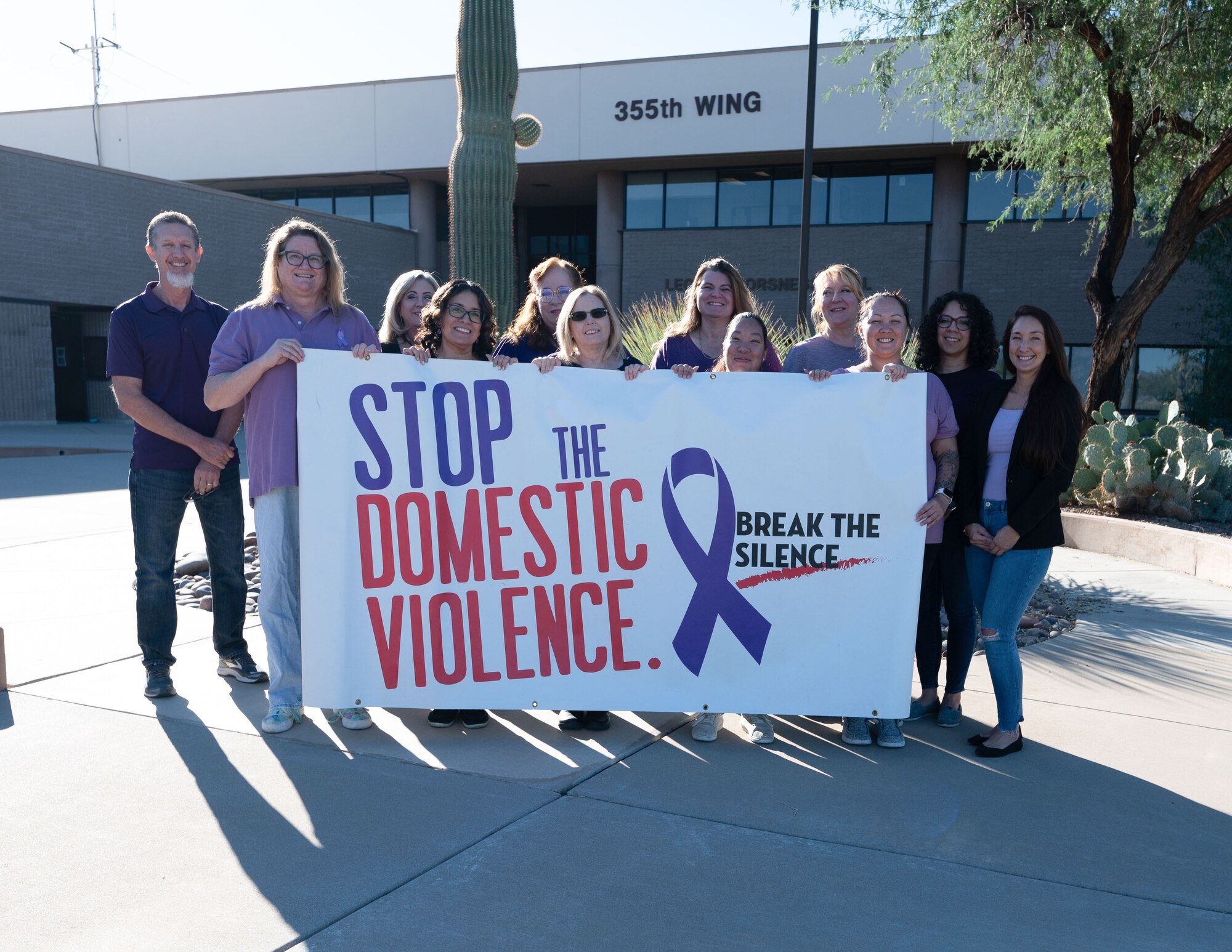 Domestic Violence Awareness month supporters stand in purple shirts outside of the 355th Wing building at Davis-Monthan Air Force Base, Ariz., Oct. 27, 2023. The color purple symbolized peace, courage, survival, honor, and a dedication to ending violence. (U.S. Air Force photo by Airman 1st Class Robert Allen Cooke III)