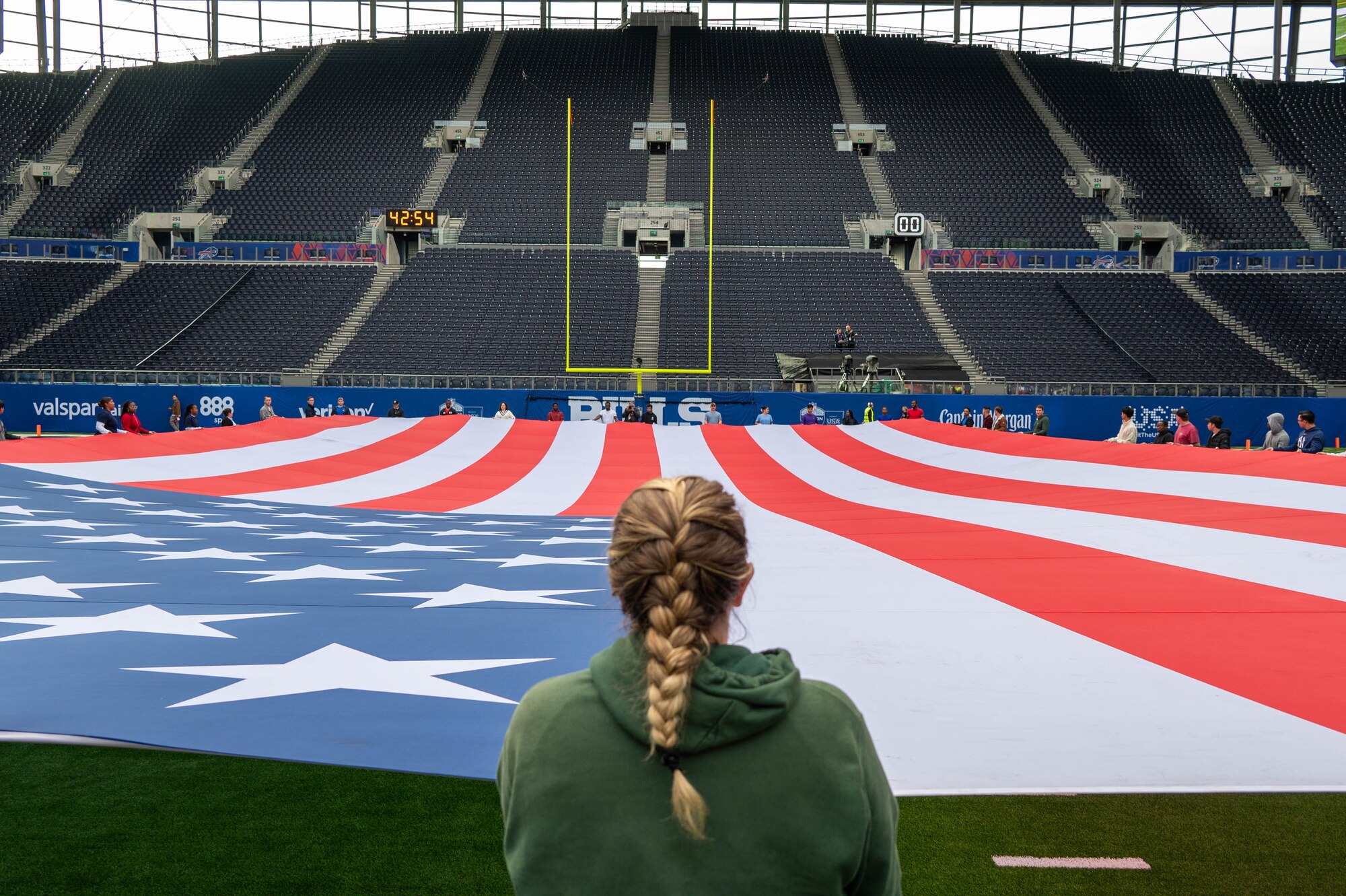 Volunteers hold an American flag on a football field during a practice
