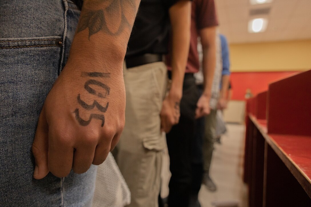 New U.S. Marine Corps recruits with Bravo Company, 1st Recruit Training Battalion, stand at attention during receiving at Marine Corps Recruit Depot San Diego, Oct. 31, 2023. During the receiving process recruits are checked for contraband, given a haircut, make a phone call home, and issued gear. (U.S. Marine Corps photo by Lance Cpl. Janell B. Alvarez)