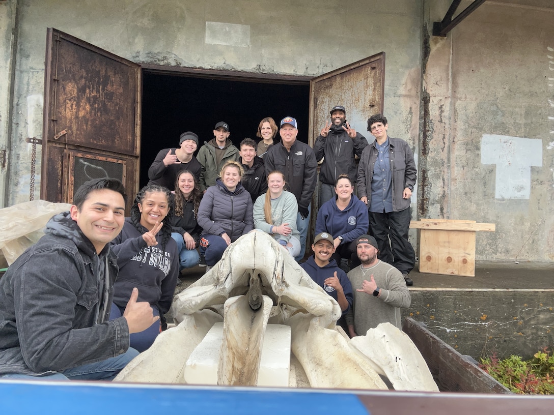 U.S. Coast Guard Cutter Kimball (WMSL 756) crewmembers pose for a photo after moving a gray whale skeleton from storage to be displayed in a new exhibit at the Aleutian Museum in Dutch Harbor, Alaska, Oct. 8, 2023. Crewmembers volunteered by assisting the museum while in port during their 85-day Bering Sea patrol. U.S. Coast Guard photo.