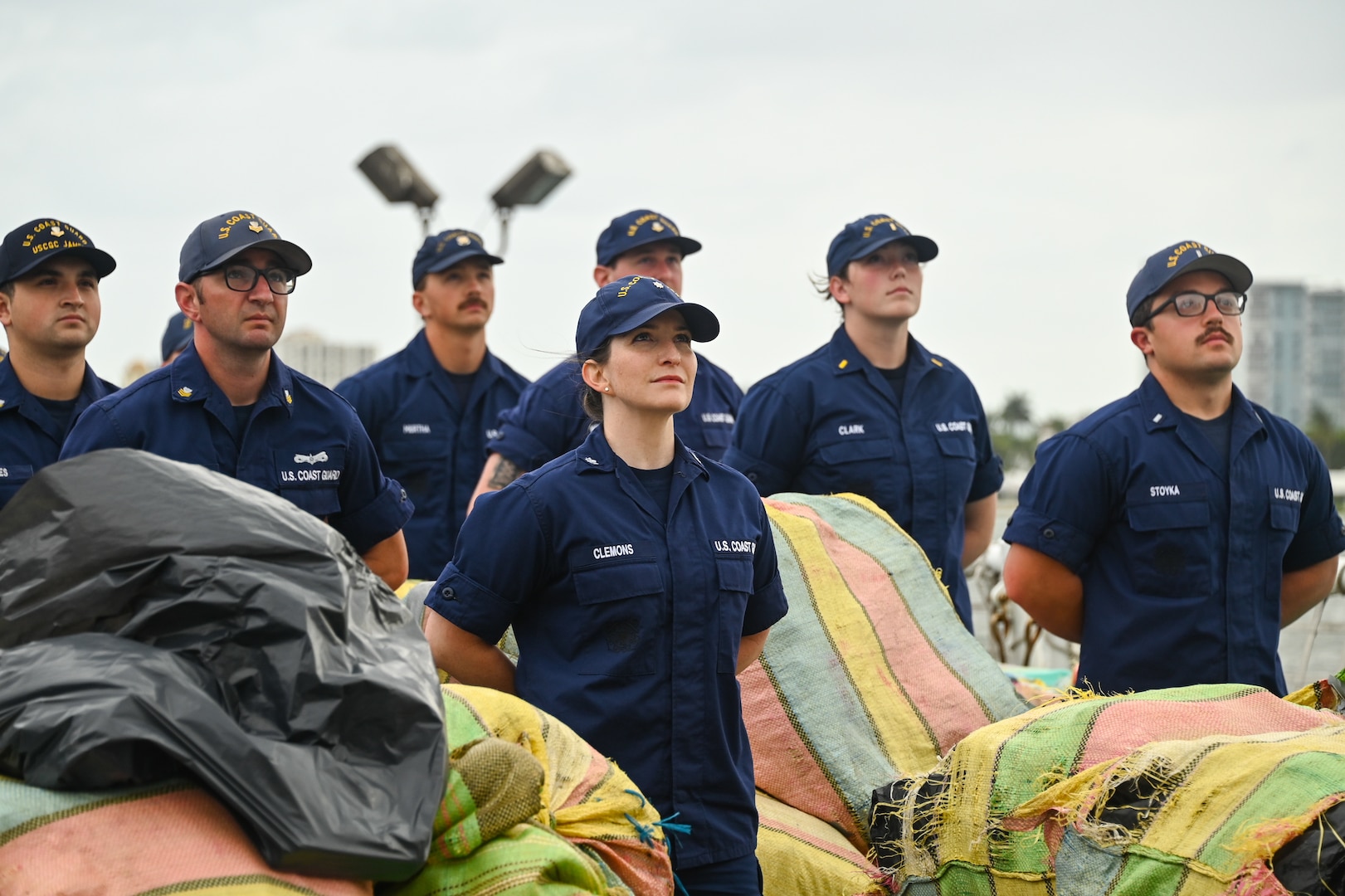 The crew of the Coast Guard Cutter James pose with more than $445 million in illegal drugs seized by Coast Guard and partner agencies in Port Everglades, Florida, Oct 26, 2023. The offload is a result of suspected drug smuggling interdictions in the Caribbean and Eastern Pacific Ocean. (U.S. Coast Guard photo by Petty Officer 2nd Class Laticia Sims.)