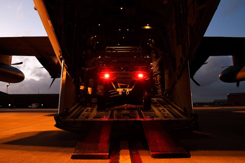 Two service members load a vehicle into an aircraft.