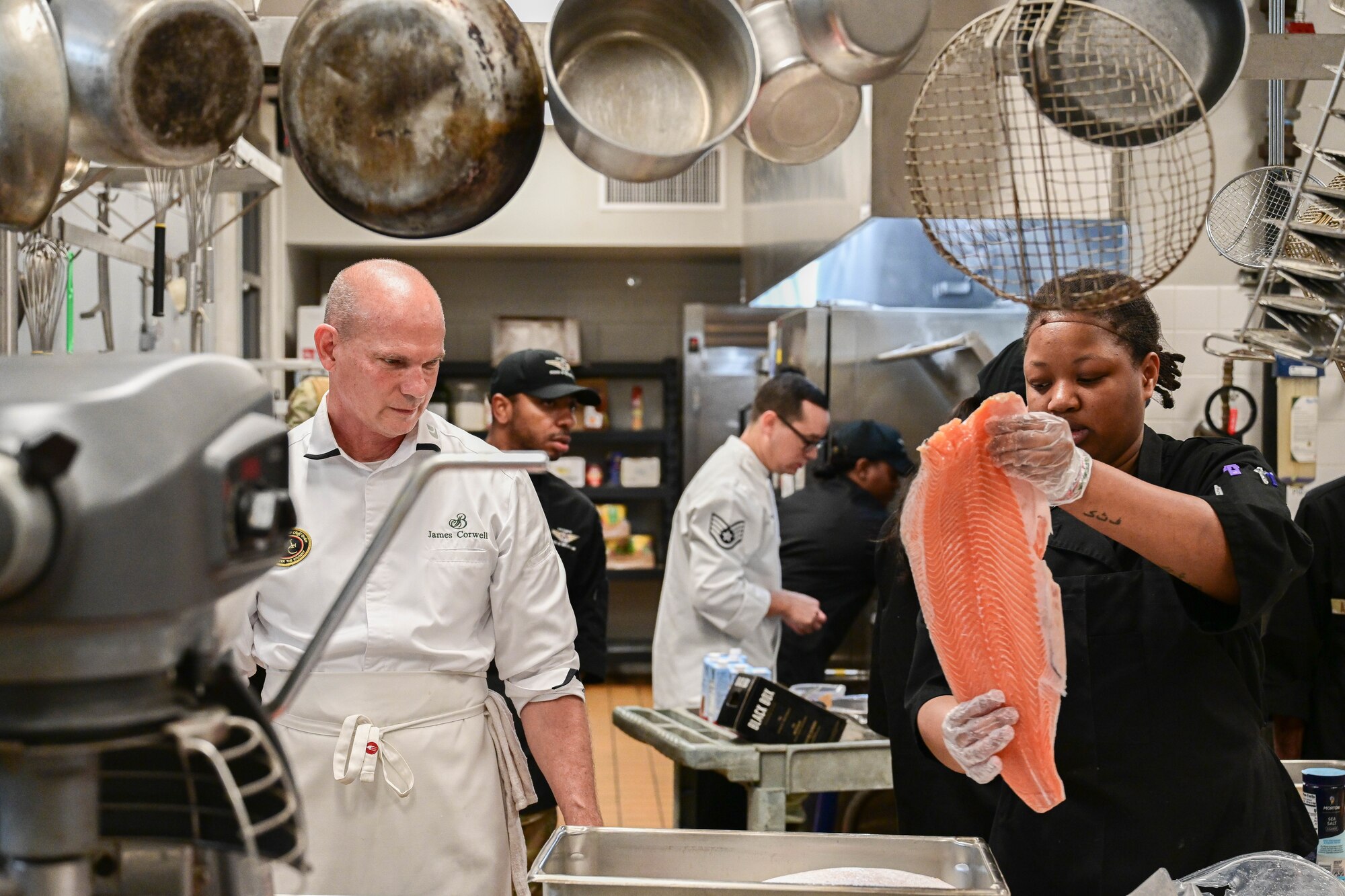 Chef James Corwell and Senior Airman Raisa Akafia prepare a fish to be cooked.