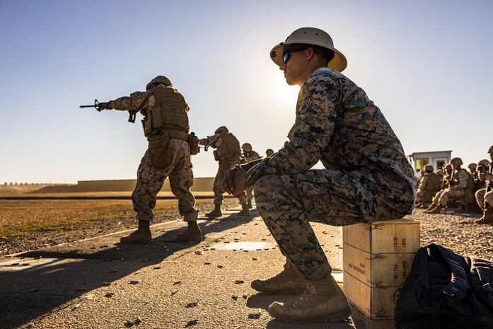A U.S. Marine Corps range coach, observes recruits shooting techniques to provide feedback during a table two course of fire at Marine Corps Base Camp Pendleton, California, Oct. 31, 2023. The table two course of fire teaches recruits the fundamentals of safety and marksmanship in combat shooting positions and rifle carries. (U.S. Marine Corps photo by Cpl. Alexander O. Devereux)