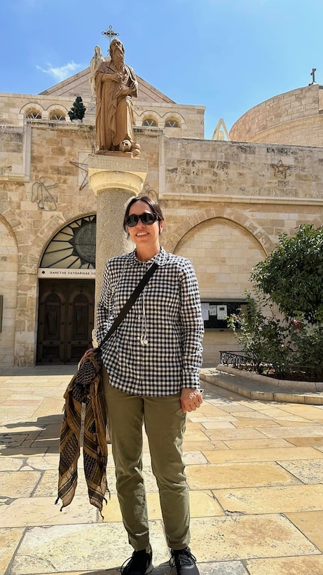 Woman stands in front of stone building