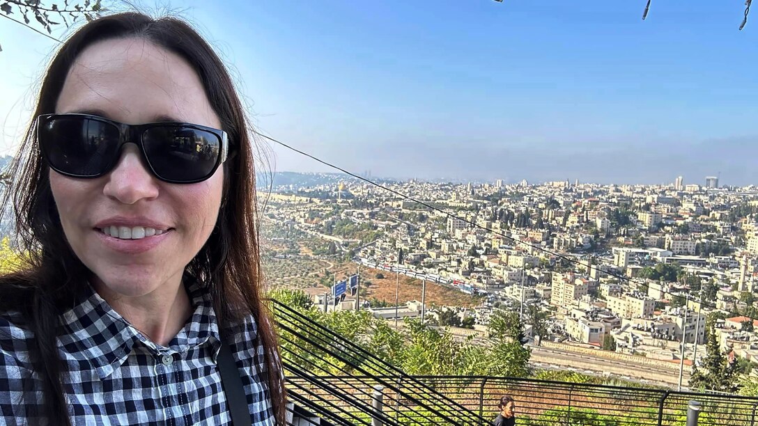 Woman stands with a city in her background