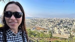 Woman stands with a city in her background