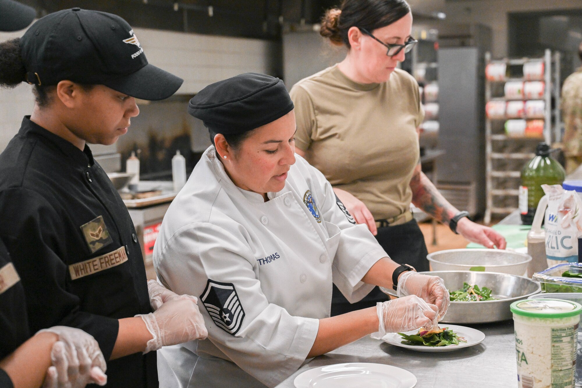 Master Sgt. Xenia Thomas shows Airman 1st Class DaJaMeka White Freeman how to prepare a salad.