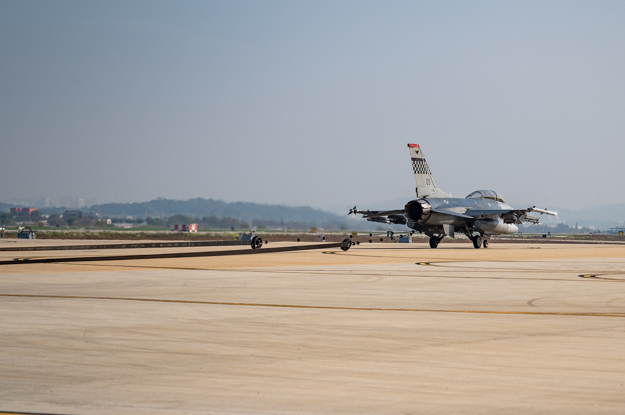 A U.S. Air Force F-16 Fighting Falcon stops on an alternate landing strip using a Mobile Aircraft Arresting System during Vigilant Defense 24 at Osan Air Base, Republic of Korea, Oct. 30, 2023. The taxiway on the flightline becomes an active air strip when the ALS is activated. VD24 is a routine training event that tests the military capabilities across the peninsula, allowing combined and joint training at both the operational and tactical levels. (U.S. Air Force photo by Staff Sgt. Thomas Sjoberg)