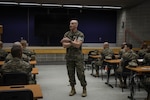 A man in a uniform addresses a classroom.