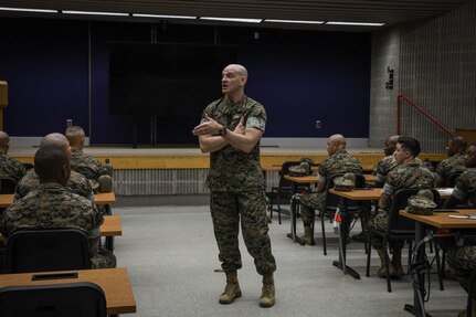 A man in a uniform addresses a classroom.